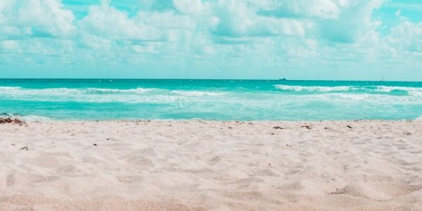 beach under blue sky and white clouds during daytime